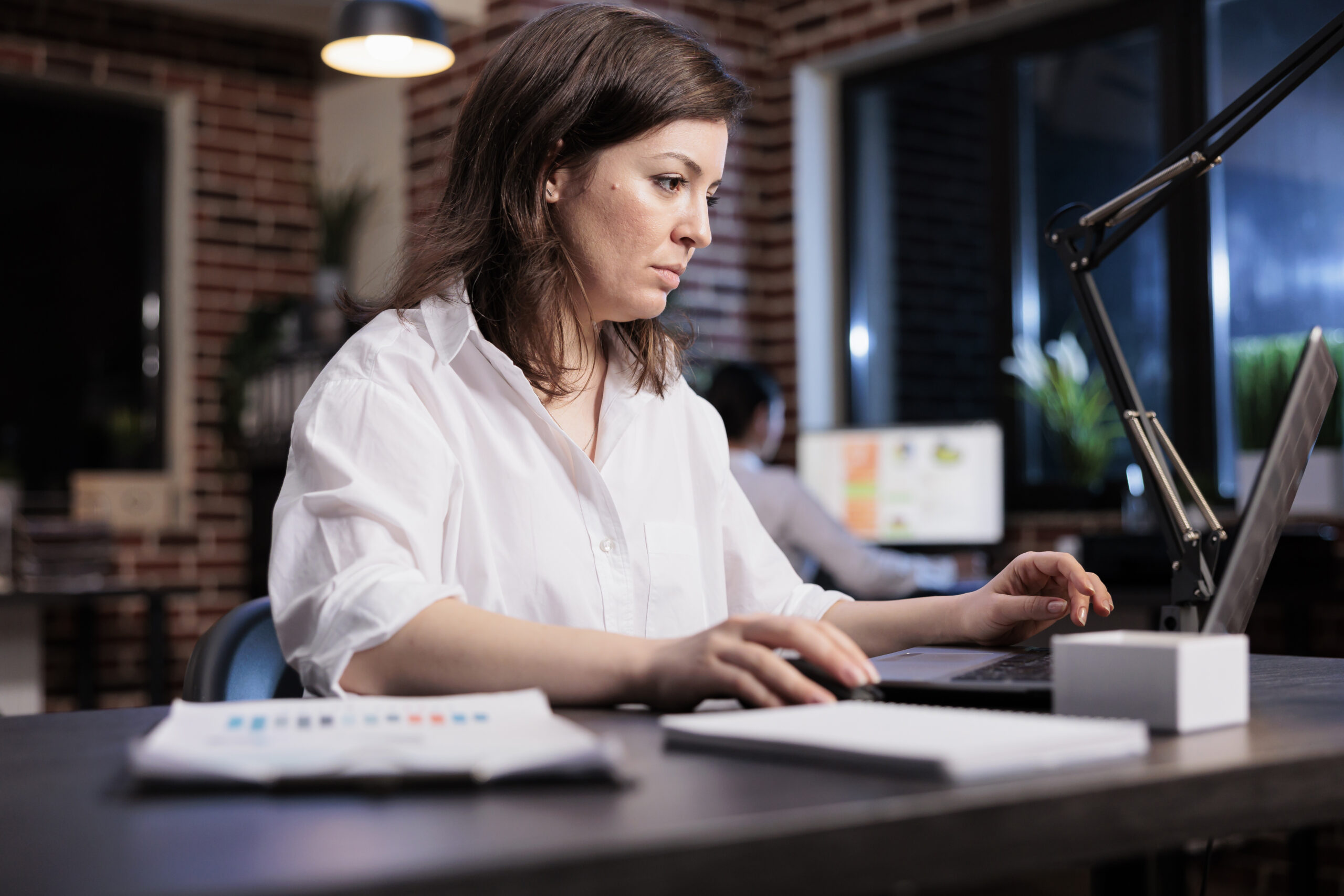 Marketing company businesswoman sitting in office workspace while reviewing accounting documentation.